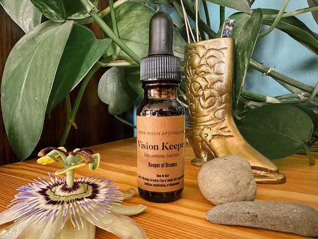 Bottle of 'Vision Keeper' with a dropper on a wooden surface with plants and a gold boot in the background. Dream Elixir 